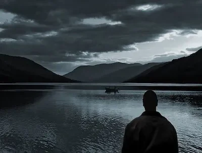 Male silhouette looking at a lake in the distance