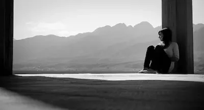 Female sitting against a pillar with mountains in the background