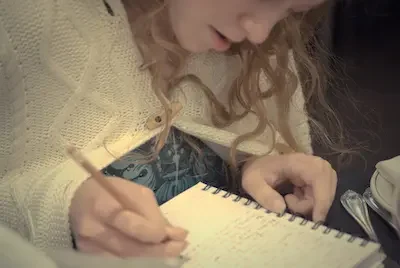 Teen girl writing in spiral notebook